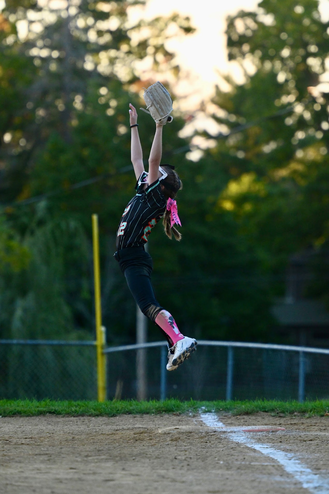 Reese leaping at first base with her glove stretched overhead.