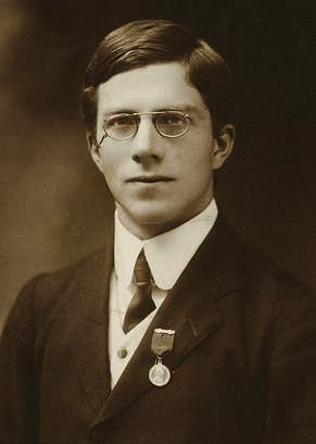 Portrait of a young Ronald A. Fisher in a suit and round wire glasses, photographed in 1913.